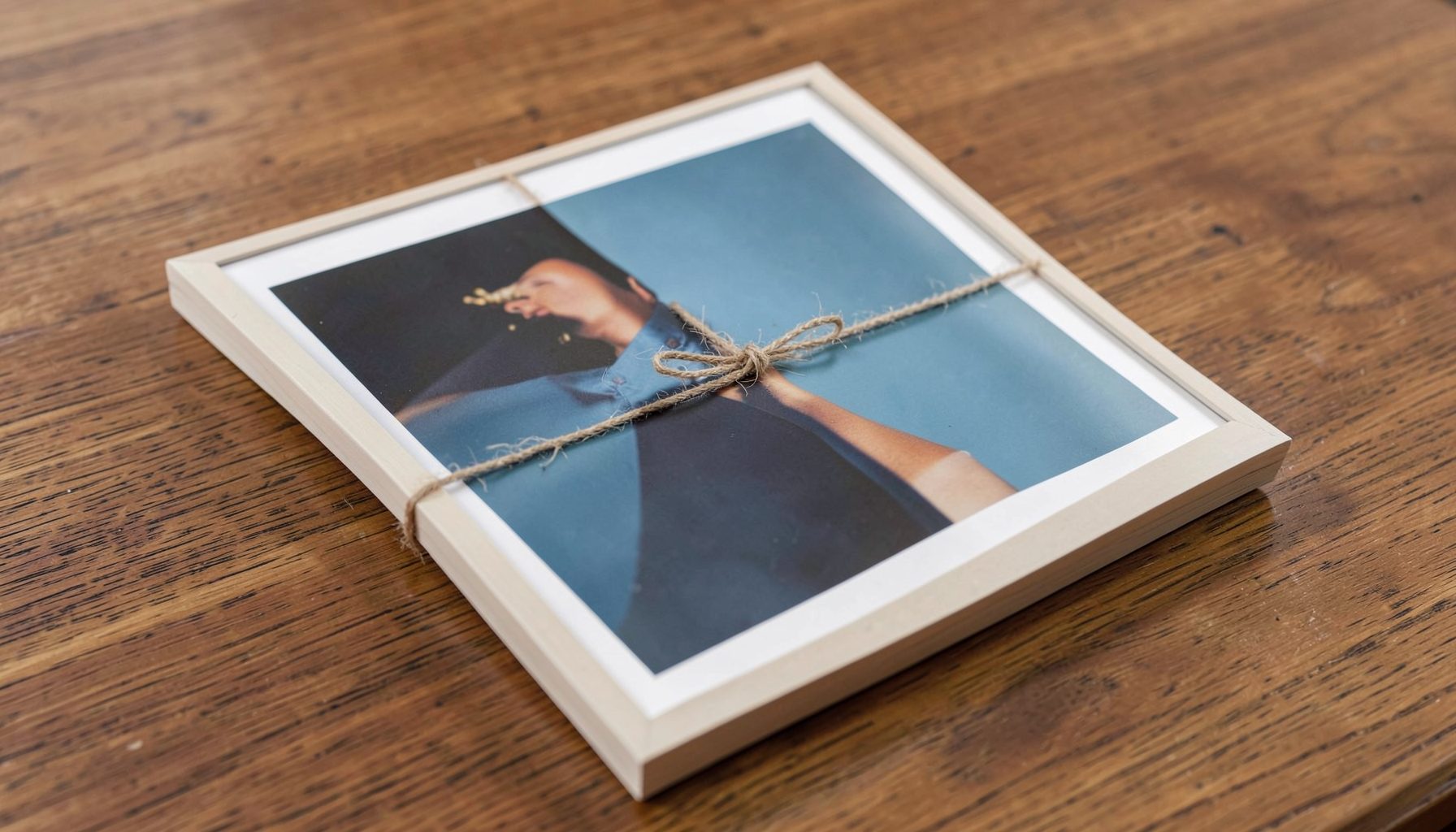 Unframed poster rolled and tied with string, resting on a wooden surface